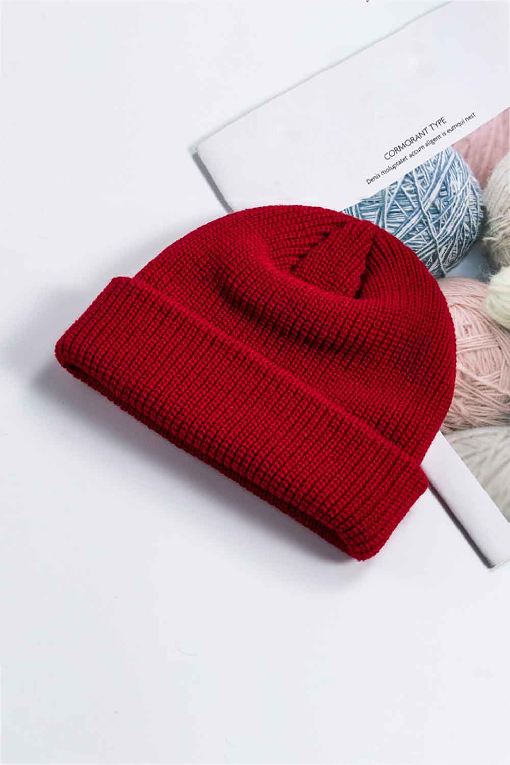 Burgundy knit cuff beanie displayed at an angle on a printed page.
