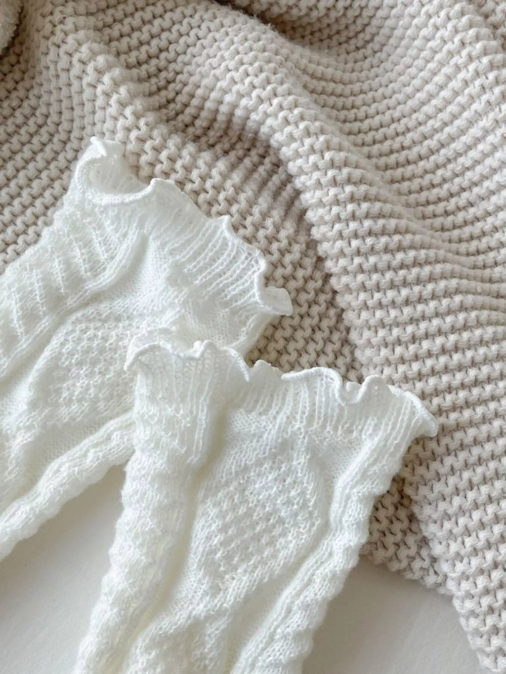 White leg warmers laid flat with the cable-knit pattern visible.
