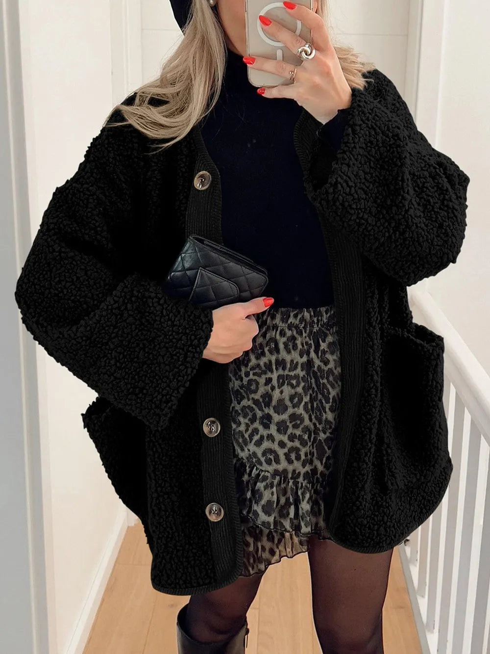 Black textured jacket worn open over a black top and leopard-print skirt.