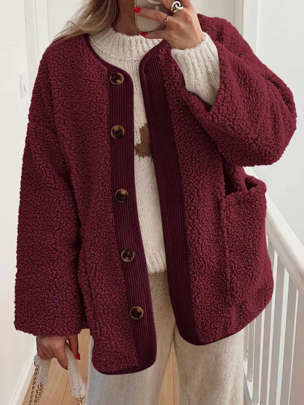 Burgundy textured jacket with contrast trim, worn over a cream sweater.