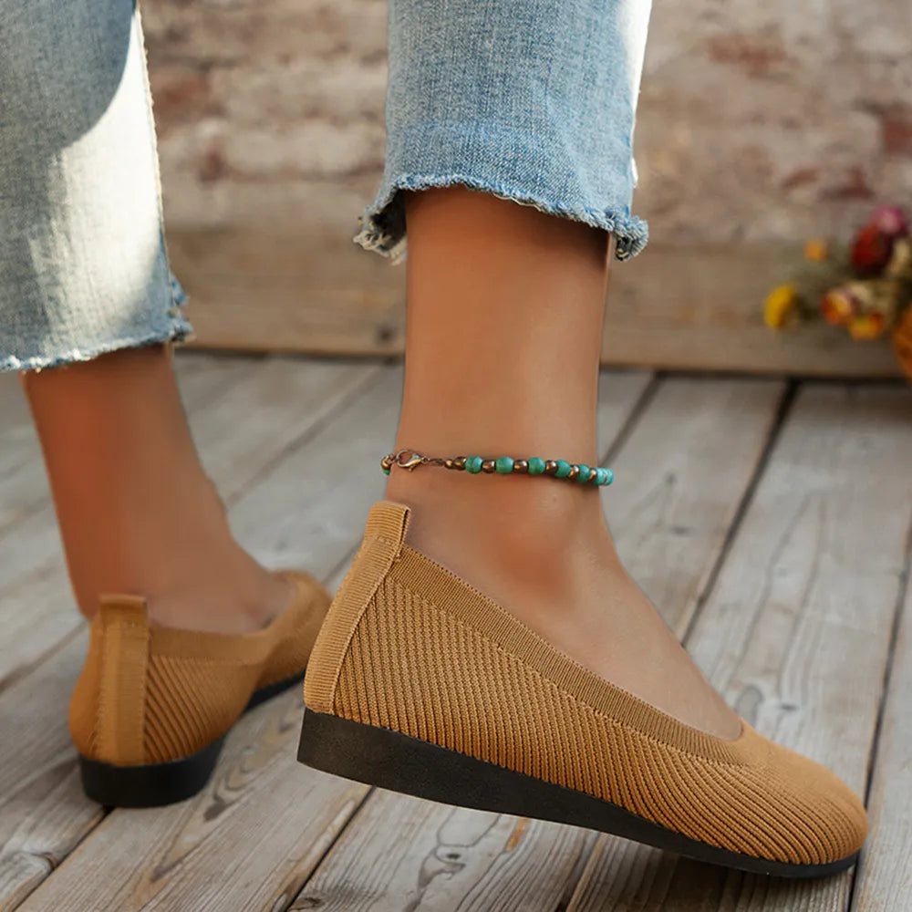 Heel and side view of caramel knit ballet flats worn with cropped jeans.