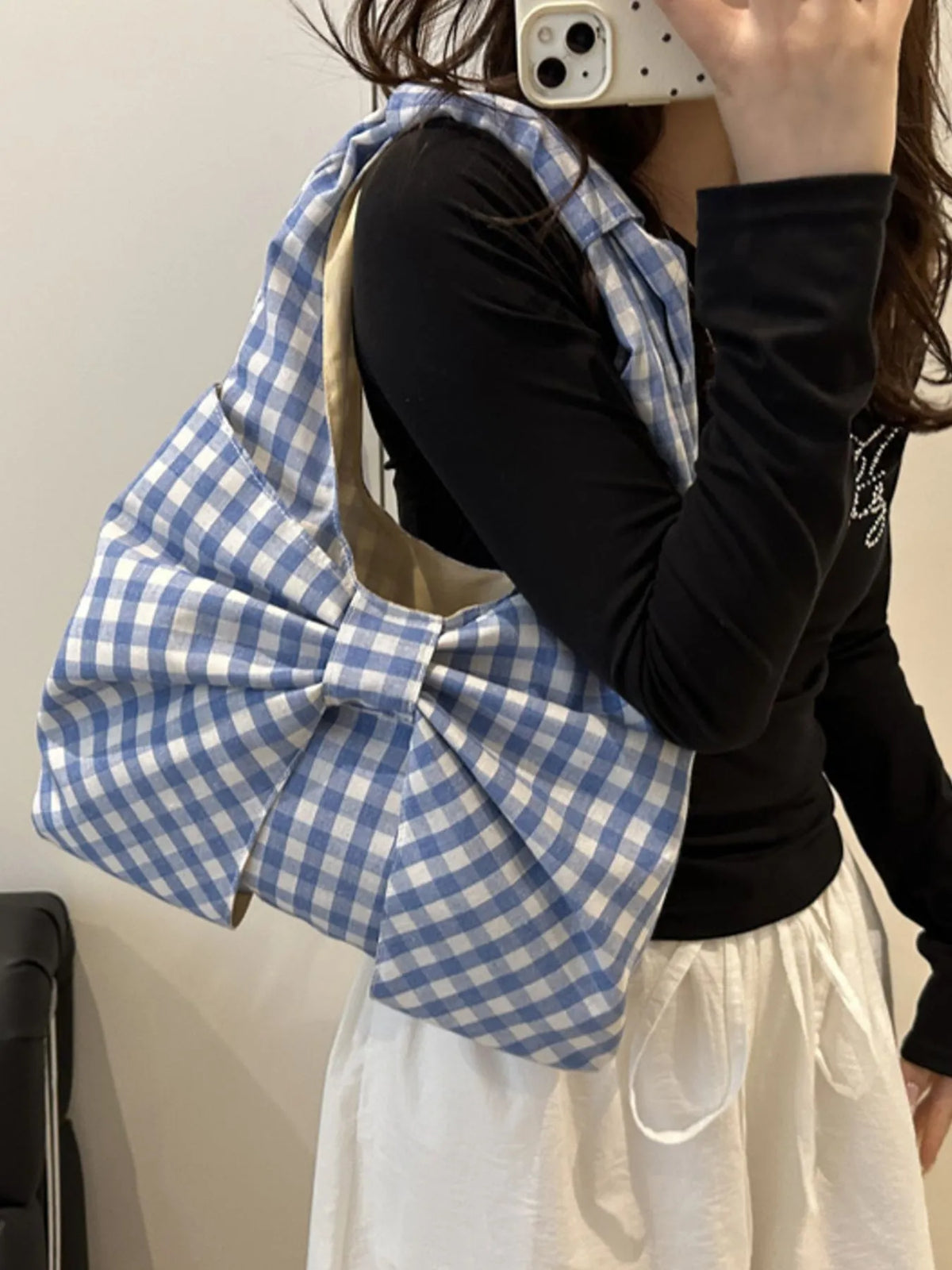 Blue and white checked bow shoulder bag shown in a front mirror view.