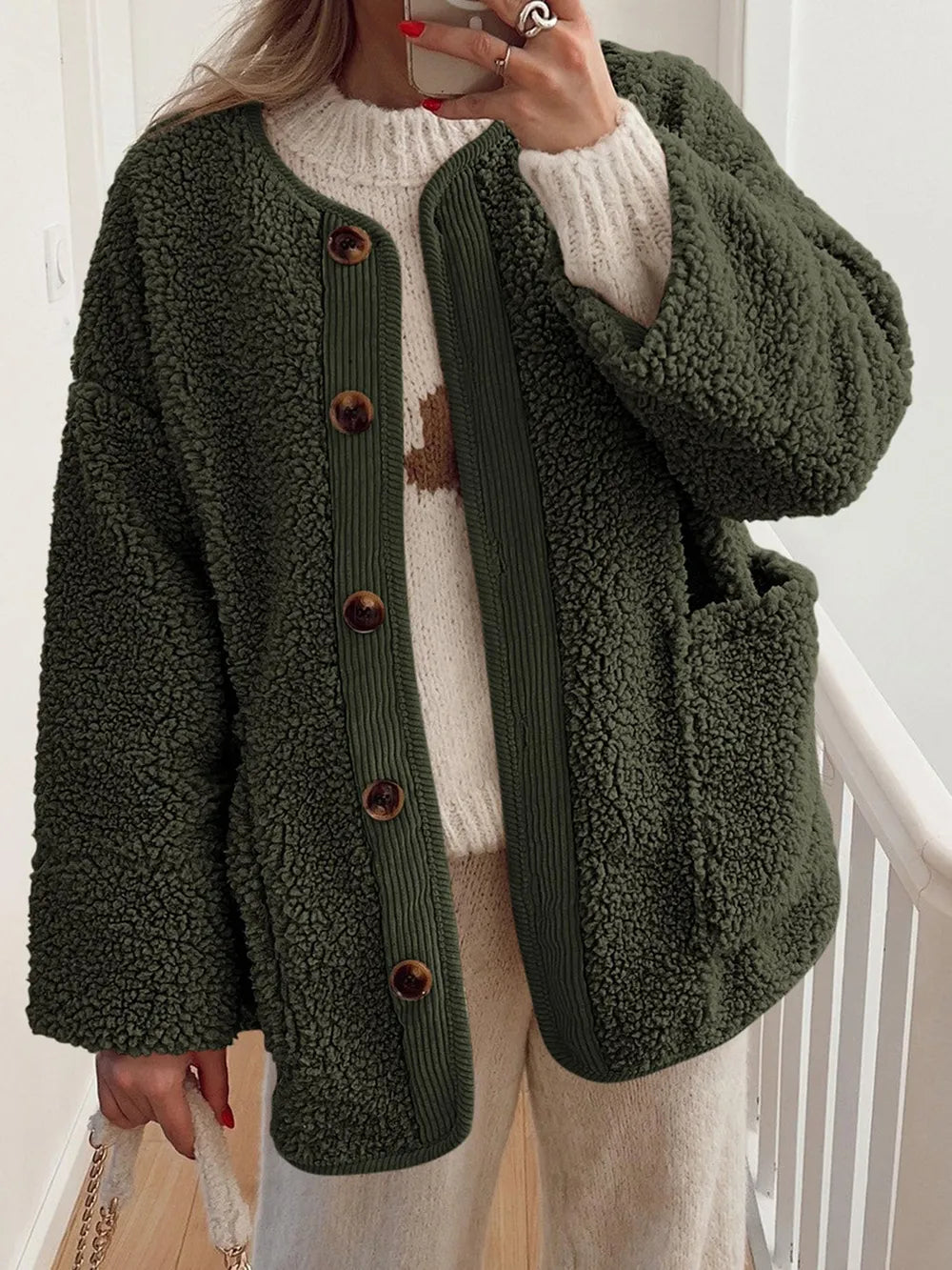 Olive green textured jacket with contrast trim, worn over a cream sweater.