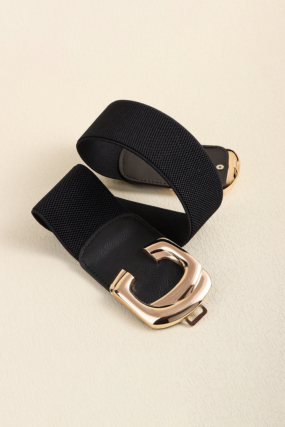 Black elastic belt loosely folded with the metal buckle ends visible.