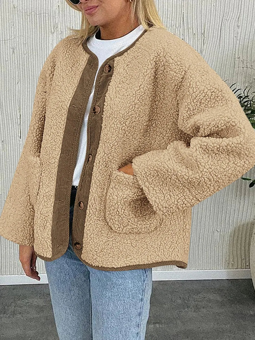 Tan textured jacket worn with a white T-shirt and jeans, showing its front patch pockets.