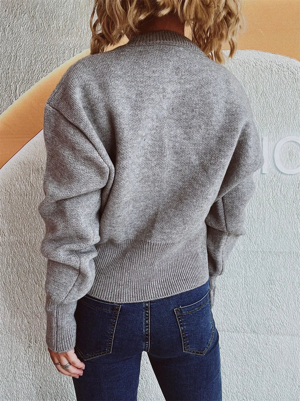 Back view of the Gray half-zip knit sweater worn with dark jeans.