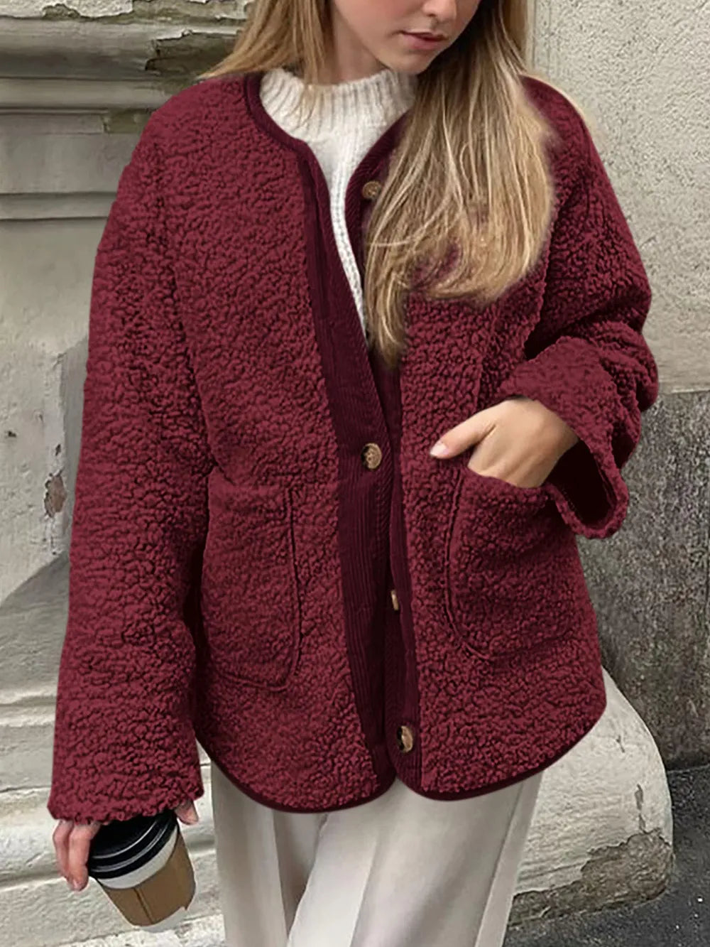 Front view of the burgundy textured jacket outdoors, with one hand in a patch pocket.